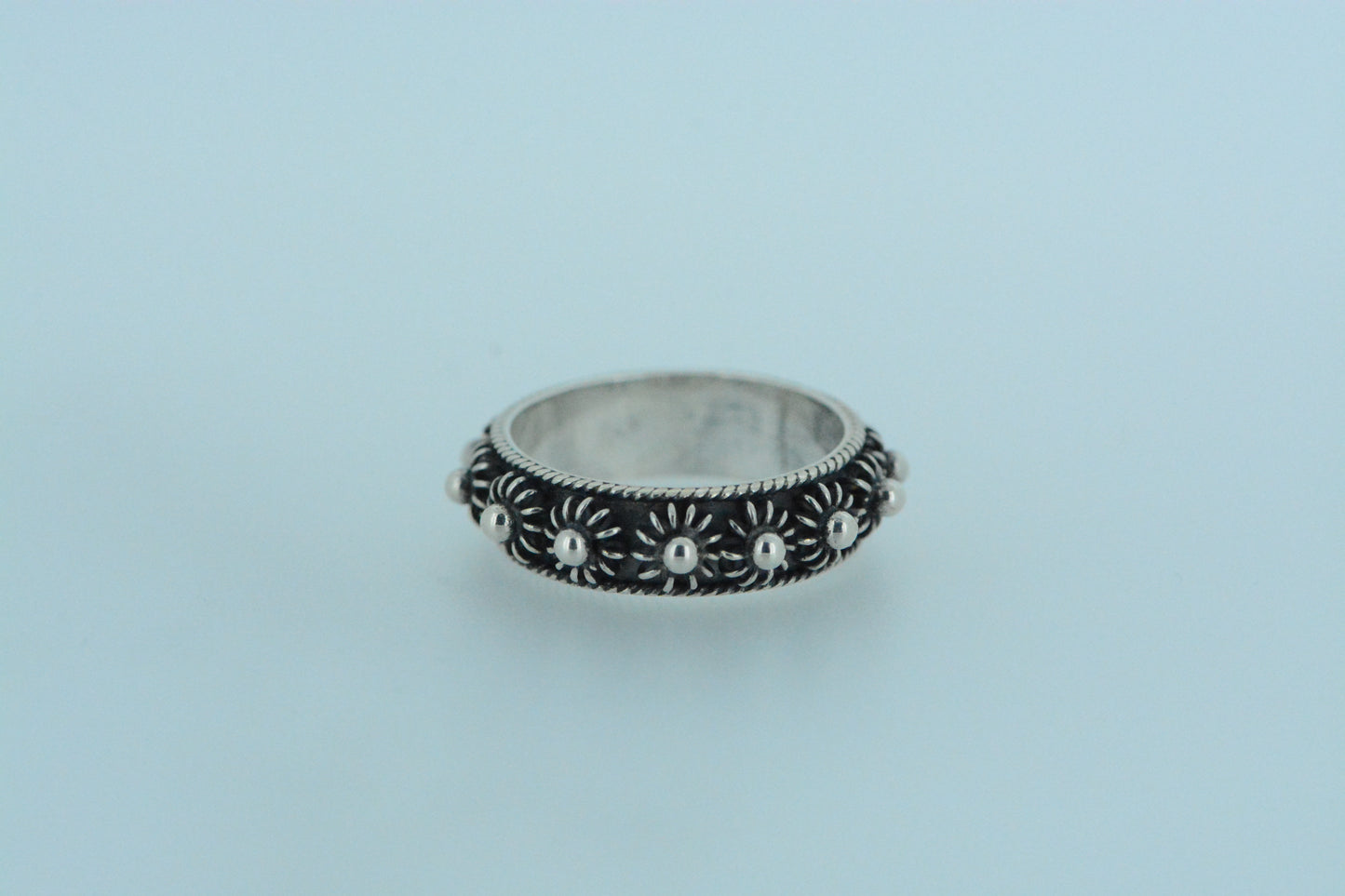 A sterling silver ring with black oxidised decoration forming floral patterns around the band.
