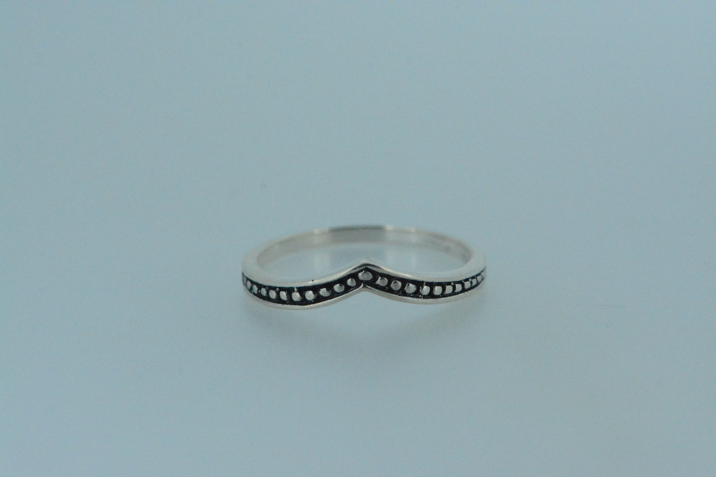 This hand made sterling silver wishbone ring has enclosed silver beads set against a dark oxidised background. Simple & elegant to be worn either alone or stacked.