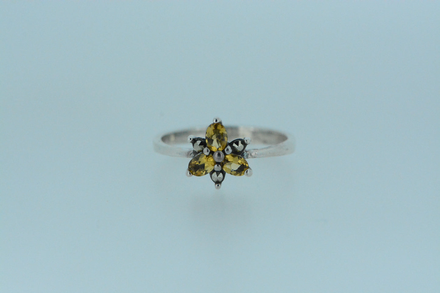 Inspired by nature, this ring presents a mini flower with three oval shaped vibrant yellow citrine gems, made in sterling silver.