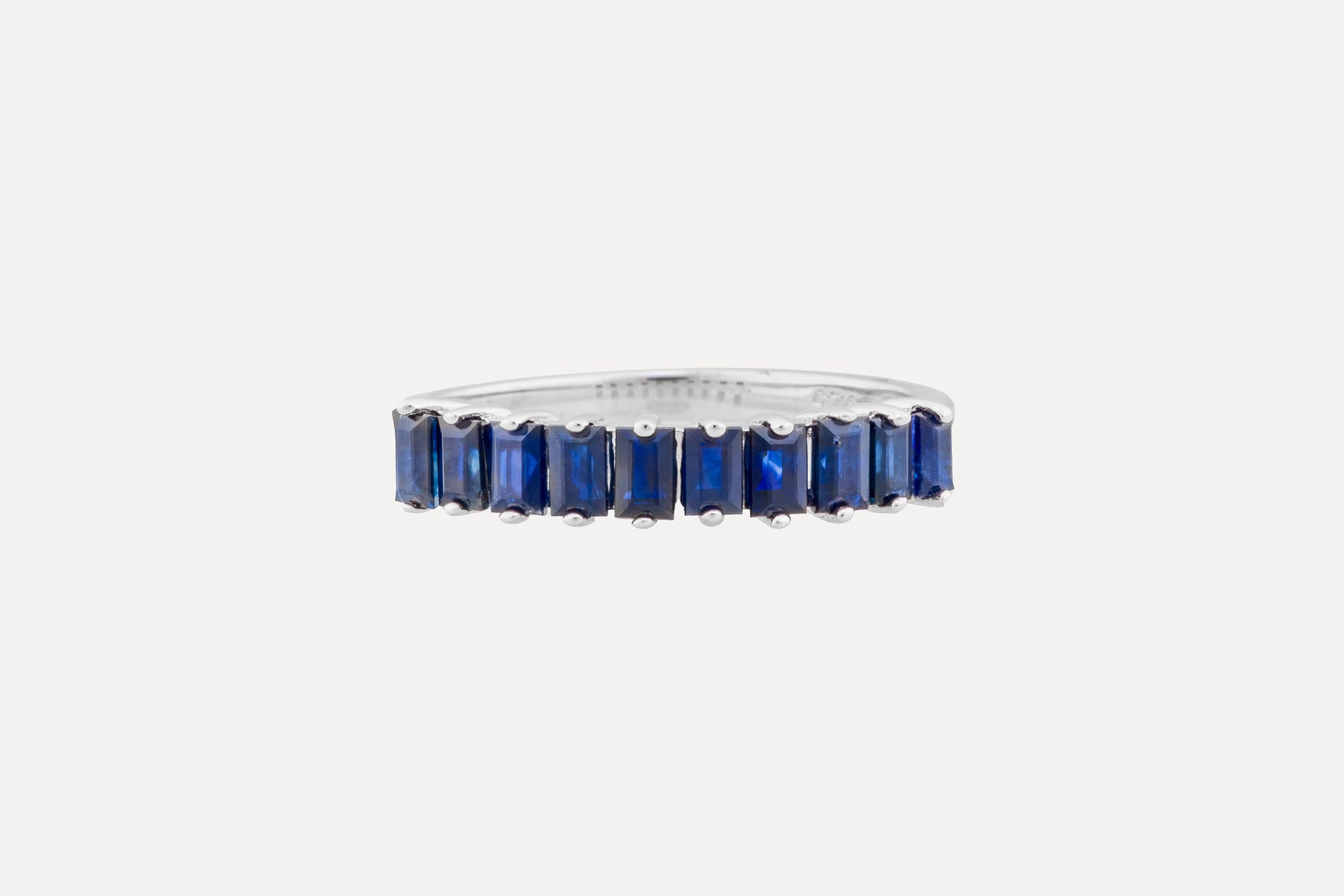 A half circle of blue baguette cut sapphires set onto a sterling silver ring with rhodium plating for a dazzling finish. Creating a simple yet sophisticated and timeless look.