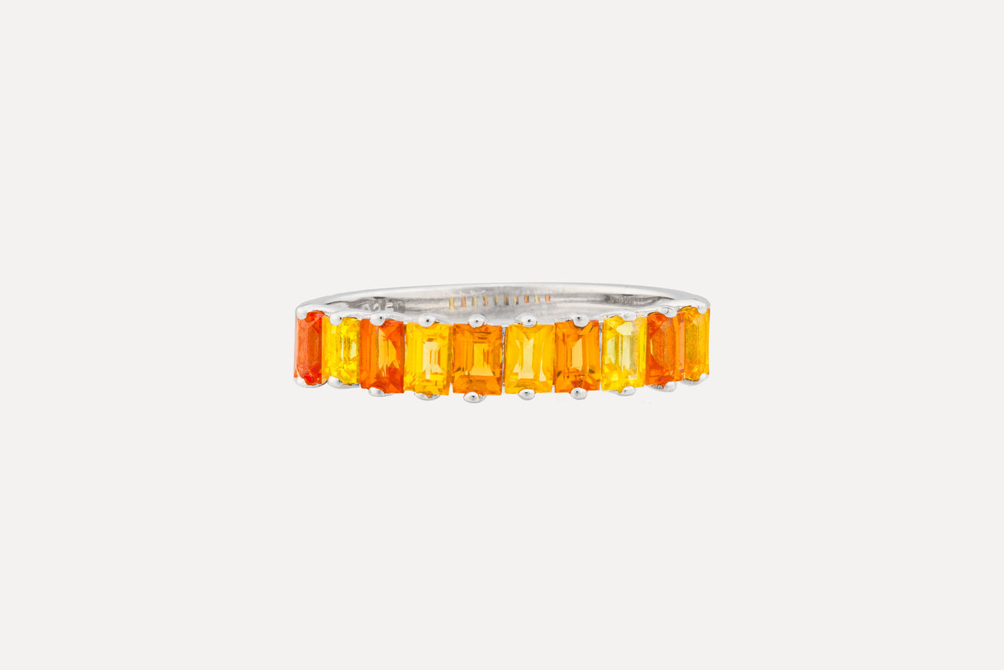 A half circle of orange & yellow baguette cut sapphires set onto a sterling silver ring with rhodium plating for a dazzling finish. Creating a simple yet sophisticated and timeless look.