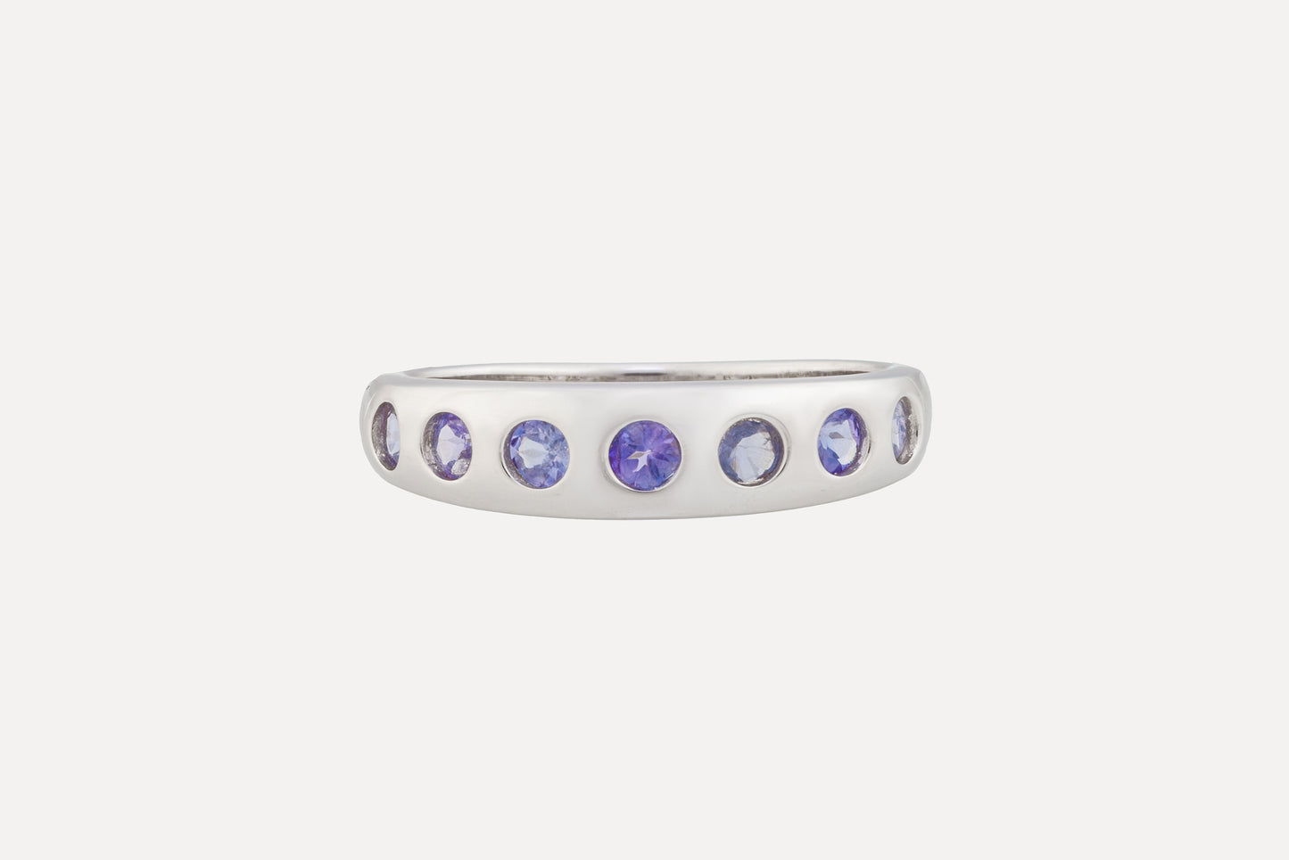 A sterling silver ring is set with a half circle of tanzanite stones with rhodium plating for a dazzling finish. A simple yet sophisticated look.