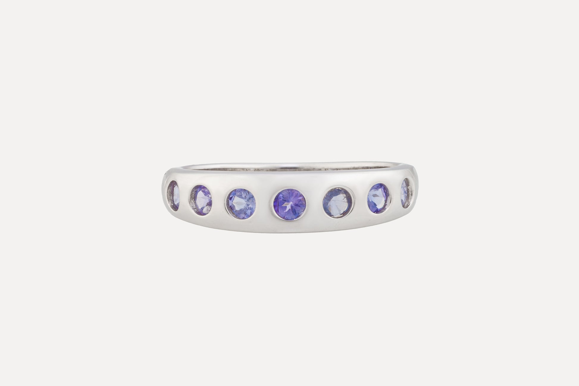 A sterling silver ring is set with a half circle of tanzanite stones with rhodium plating for a dazzling finish. A simple yet sophisticated look.