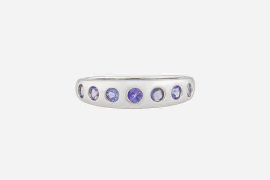 A sterling silver ring is set with a half circle of tanzanite stones with rhodium plating for a dazzling finish. A simple yet sophisticated look.
