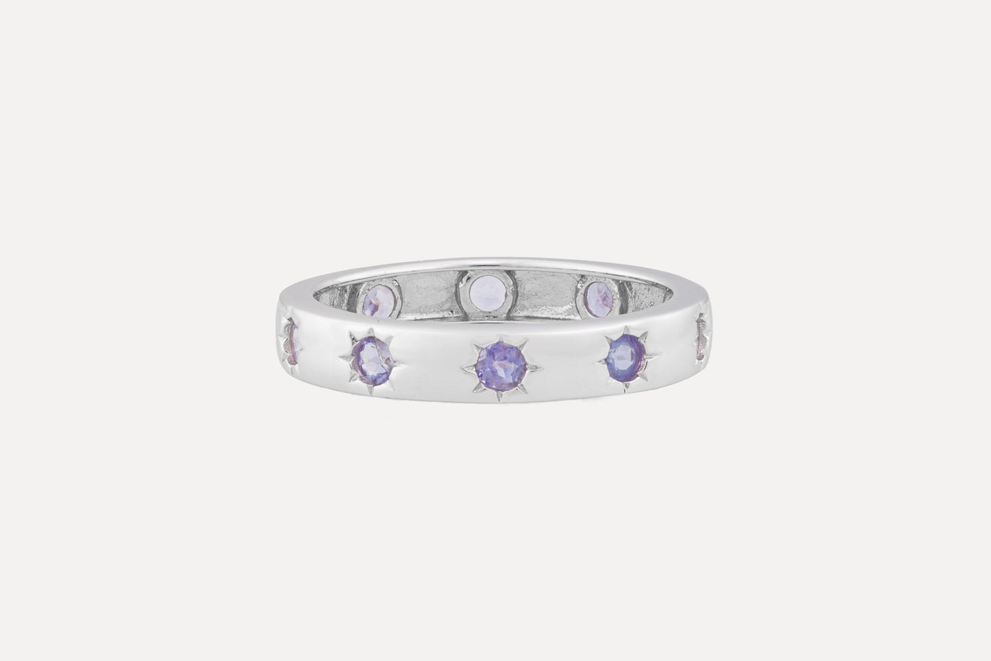 A sterling silver ring is set with a full circle of tanzanite stones with rhodium plating for a dazzling finish. A simple yet sophisticated look.