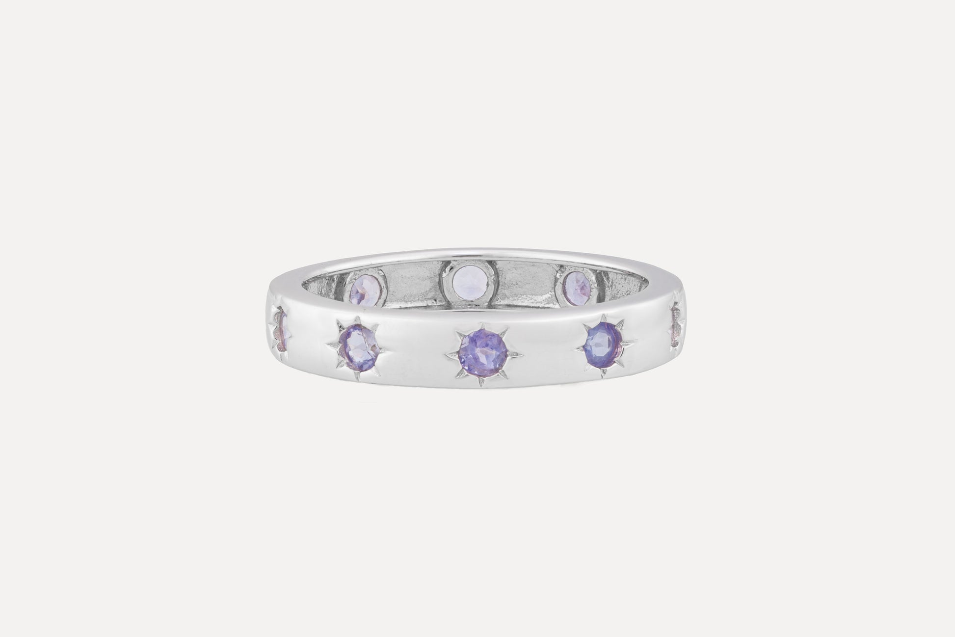 A sterling silver ring is set with a full circle of tanzanite stones with rhodium plating for a dazzling finish. A simple yet sophisticated look.