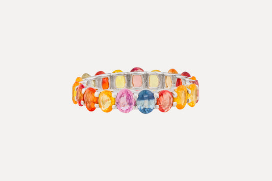 Crafted in sterling silver with a full circle of multi-coloured oval cut sapphires in a narrow claw setting. Finished in rhodium plating for a dazzling look.