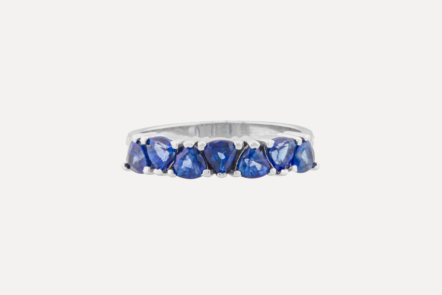 Trilliant cut classic blue sapphire half circle eternity ring set on a sterling silver band ring with rhodium plating.