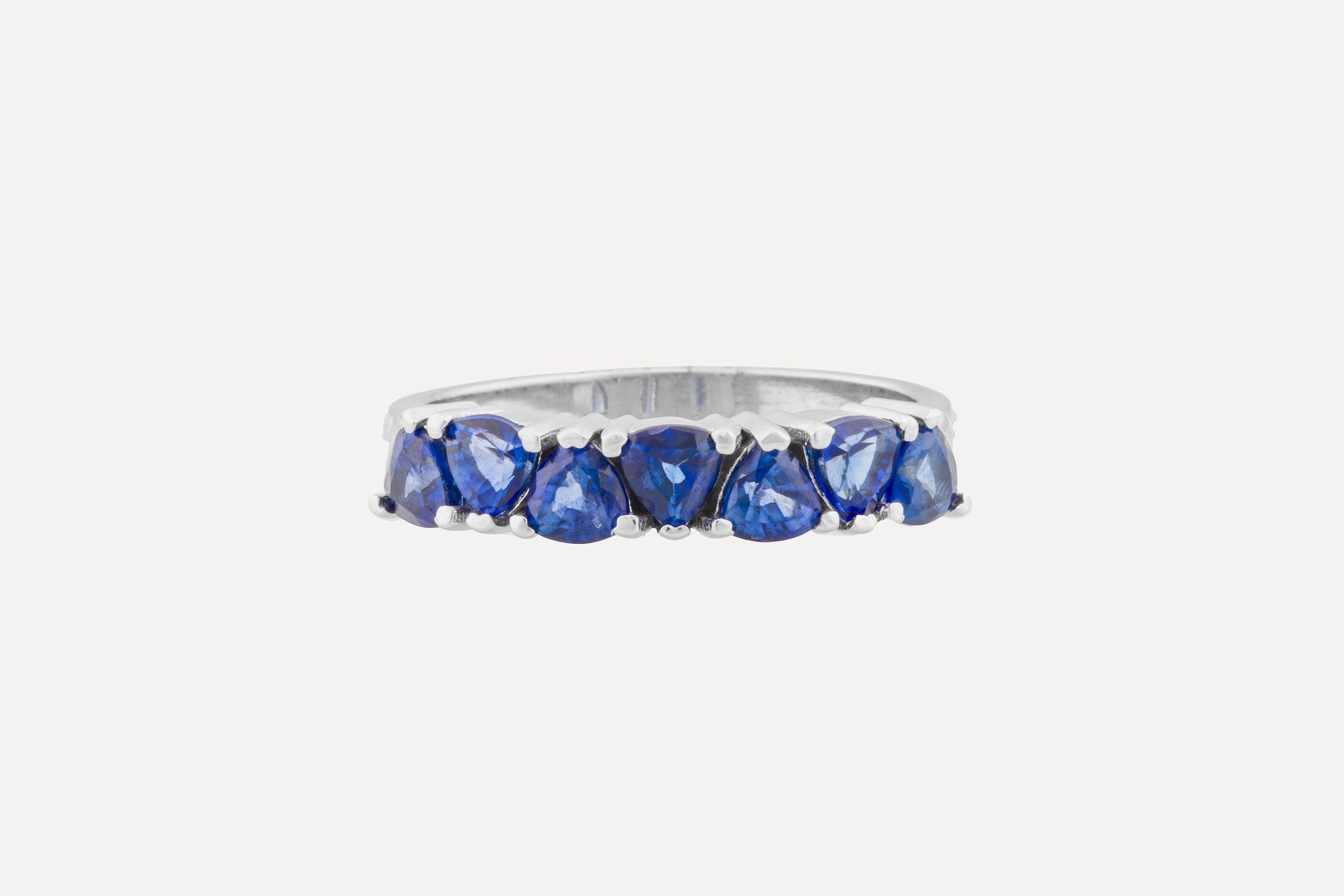 Trilliant cut classic blue sapphire half circle eternity ring set on a sterling silver band ring with rhodium plating.