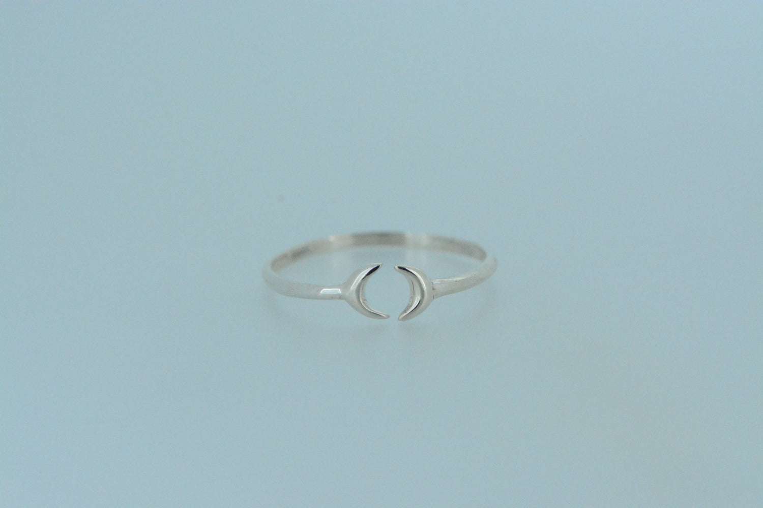 This dainty hand made sterling silver band ring, features two crescent moons that come together at the front. The open design allows for flexibility in fitting.