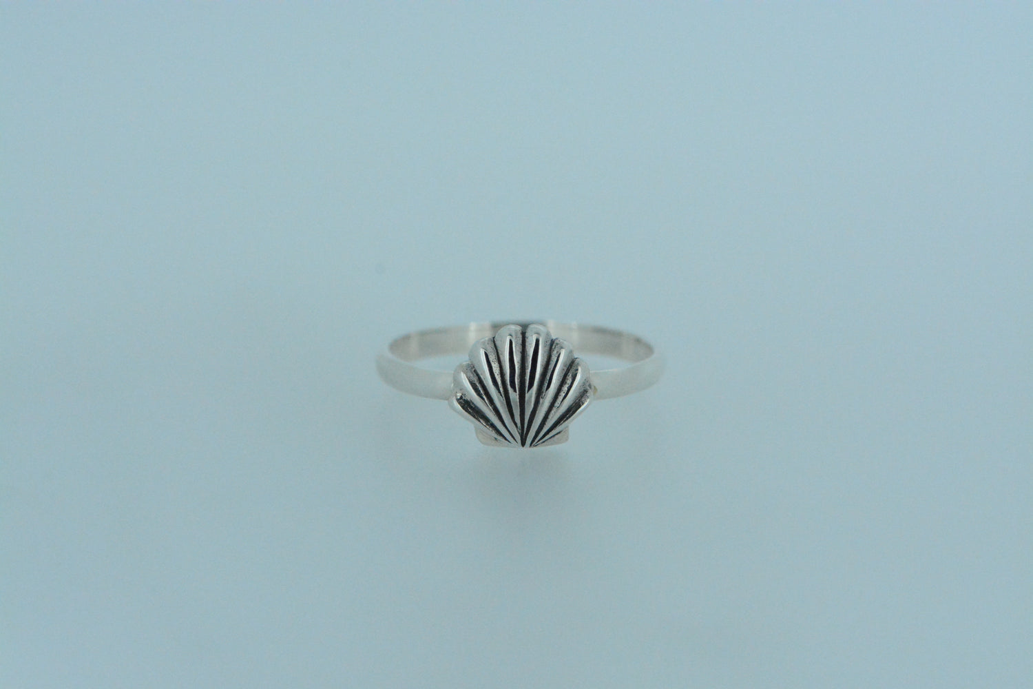 Inspired by the beauty of the sea, this delicate design features a finely detailed shell set on a sterling silver band ring. Handmade with an elegant seaside vibe.