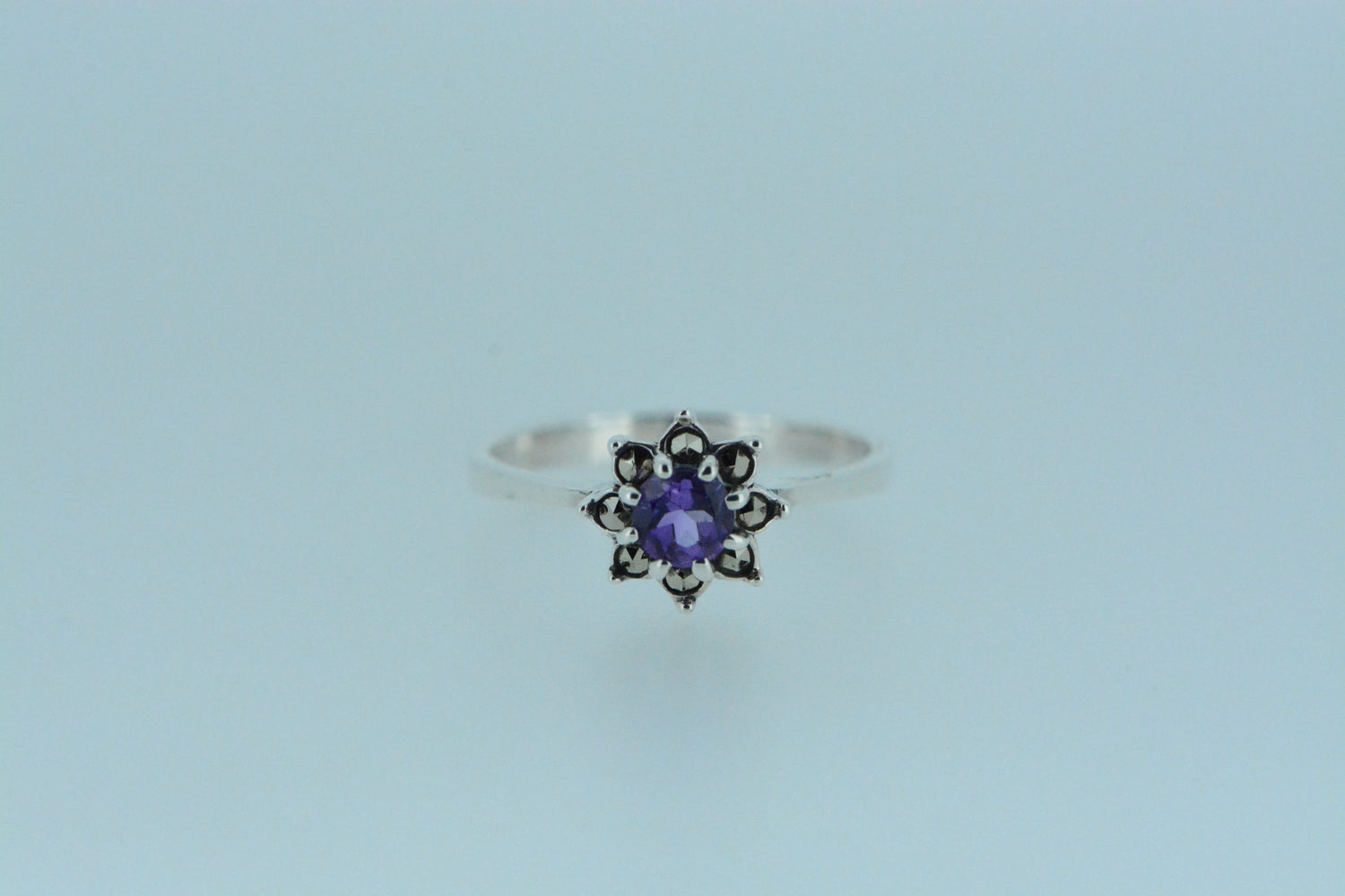 A sterling silver ring with a marcasite and an amethyst flower design.