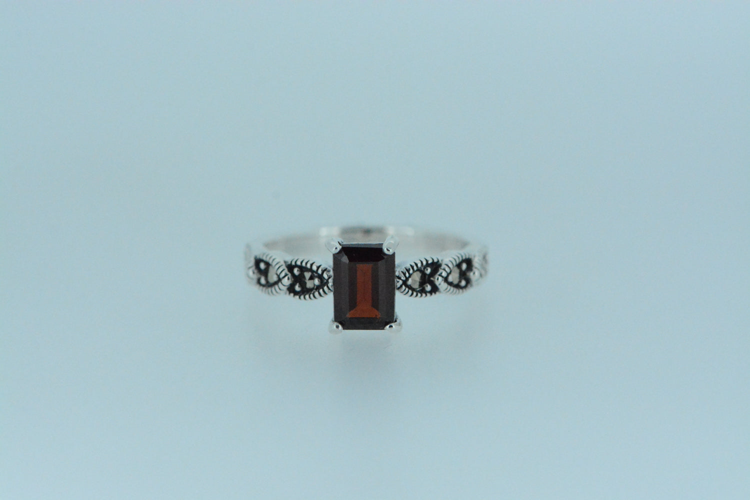 This African garnet with rectangular shape has a dark deep red colour on a sterling silver ring decorated with marcasite on the front band, a good choice with the birthstone for the month of January.