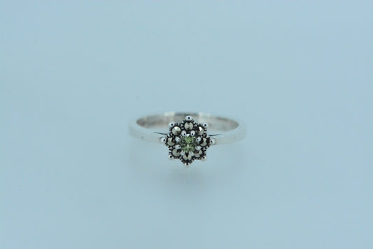 Inspired by nature, a small round peridot stone in a pronged setting with a marcasite halo resembling a floral design.