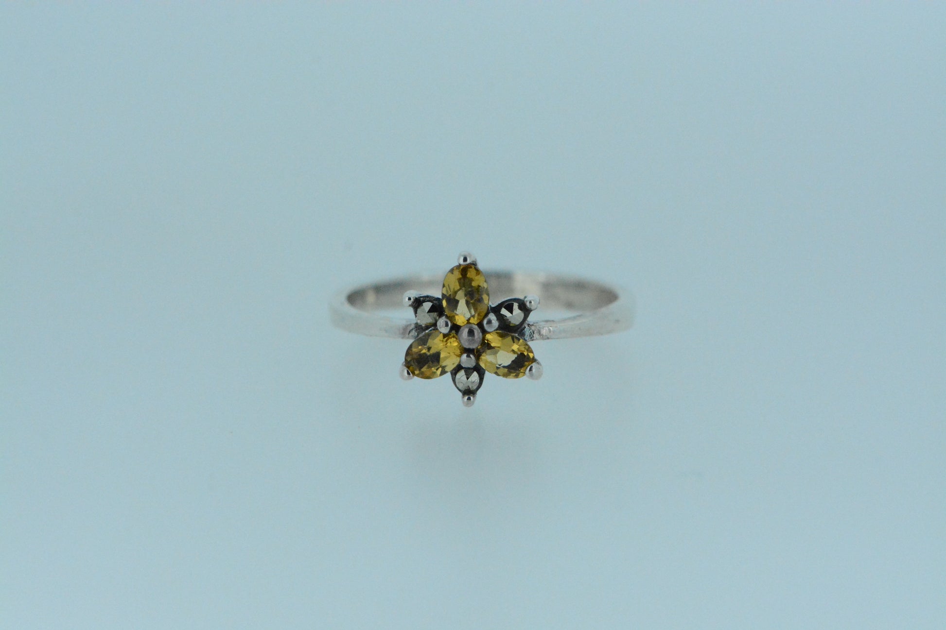 Inspired by nature, this ring presents a mini flower with three oval shaped vibrant yellow citrine gems, made in sterling silver.